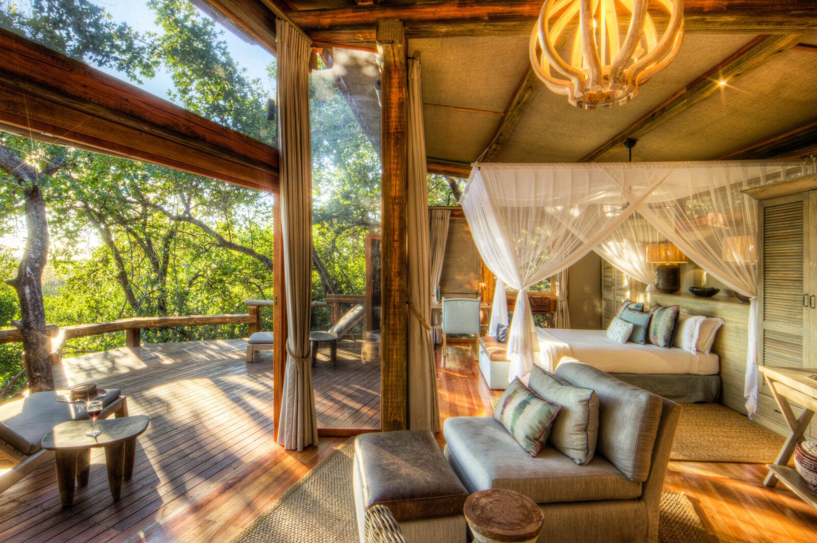 Camp Okavango luxury guest room with lounging area four poster bed and balcony