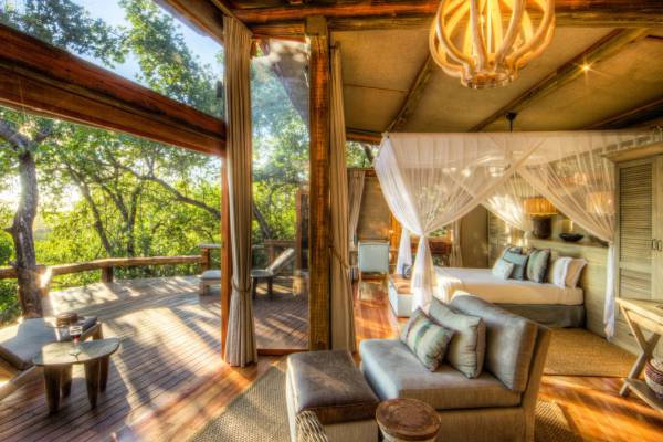 Camp Okavango luxury guest room with lounging area four poster bed and balcony