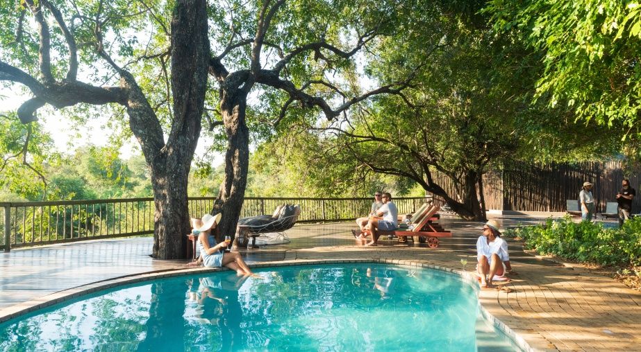 Sabi Sabi poolside with people sitting chatting under the trees