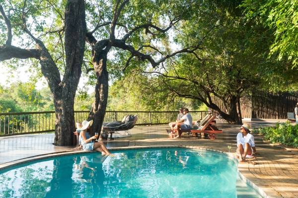Sabi Sabi poolside with people sitting chatting under the trees
