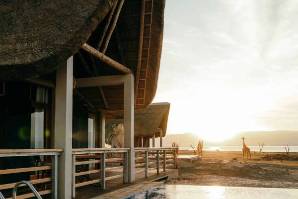 Pool next to thatched chalet with sunsetting
