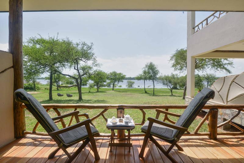 Two armchairs and coffee table on a deck overlooking green grass trees and river