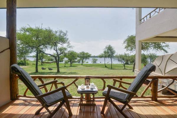 Two armchairs and coffee table on a deck overlooking green grass trees and river