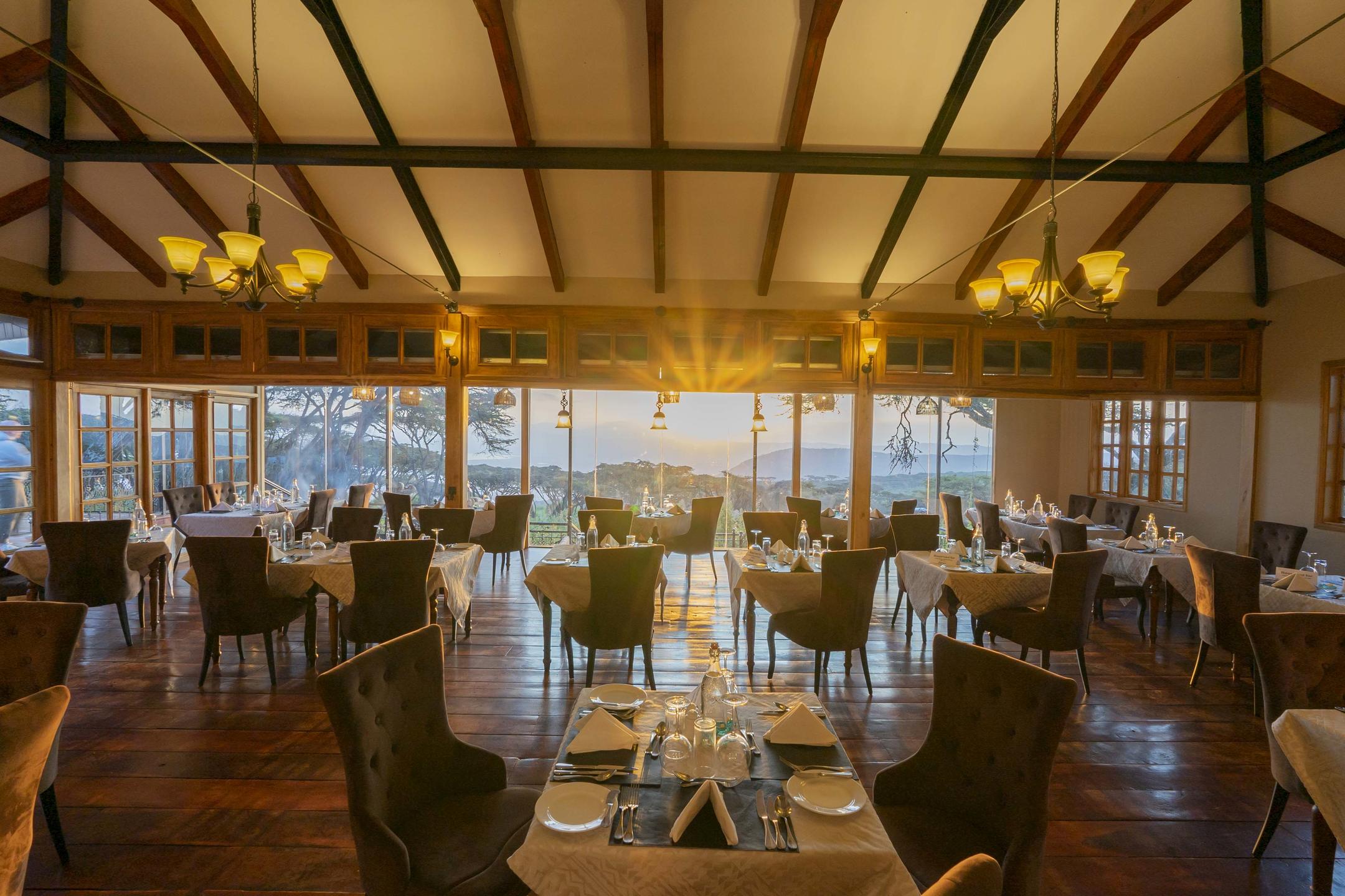Dining room with wooded floors and set tables with sun setting and shining through the space