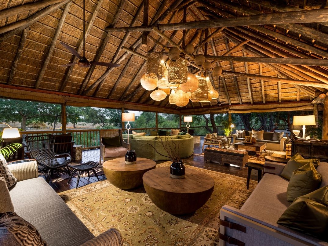 Sabi Sabi lounge beneath thatched roof with lush sofas and wooden tables