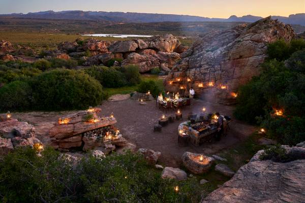 Bushmans Kloof lamp lit outdoor dining amongst rock formations and greenery