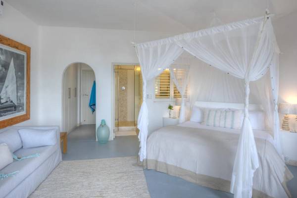 Hotel suite with sofa and four poster bed with mosquito net