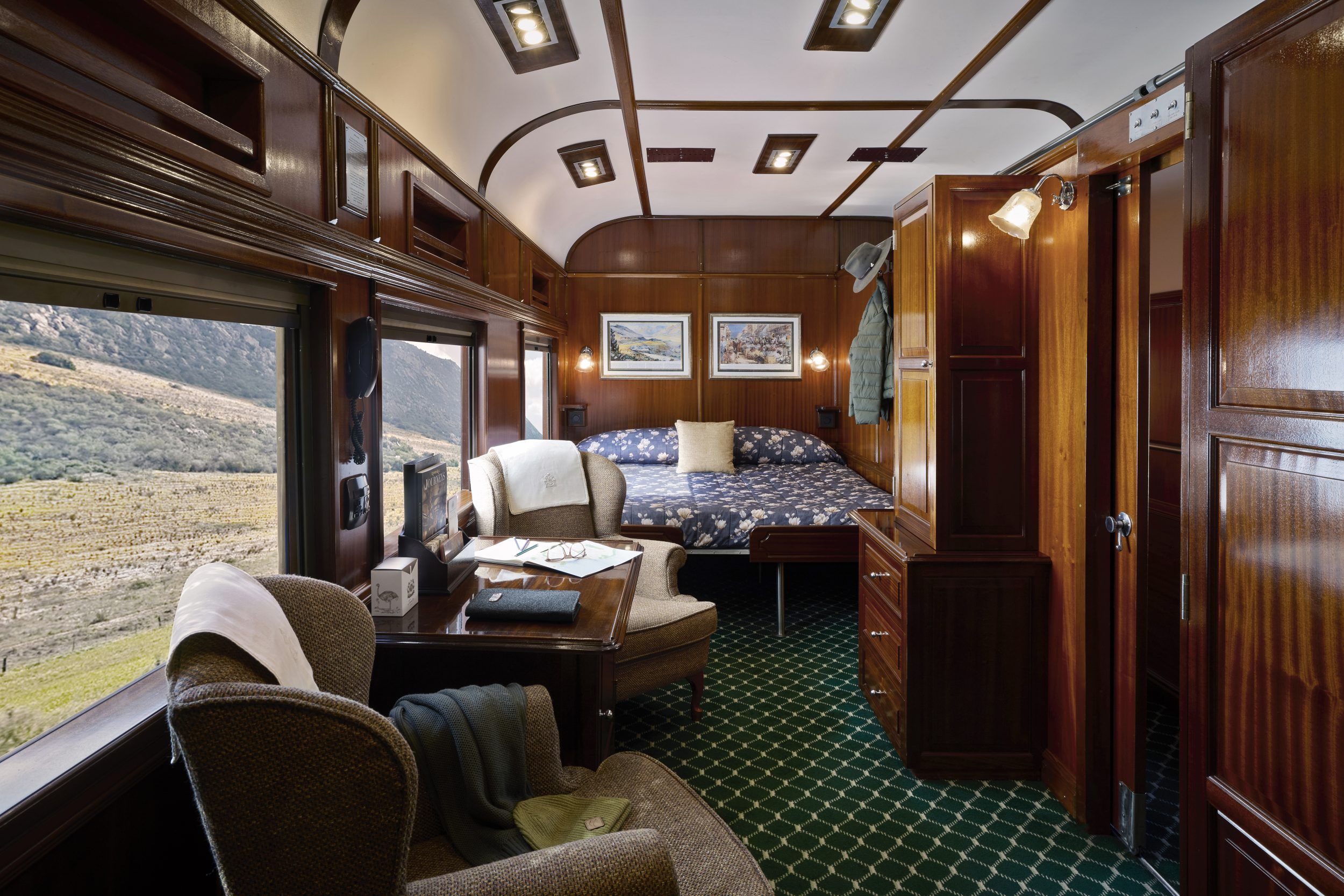 Rovos Rail wood panelled cabin with double bed and two armchairs