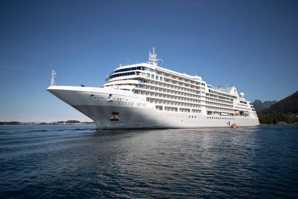 Silver Muse Ship, a luxury white cruise line, viewed from below on a deep blue sea with clear blue sky in the background