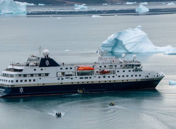 Spitsbergen cruise ship on an icy ocean with ice bergs floating in the distance.