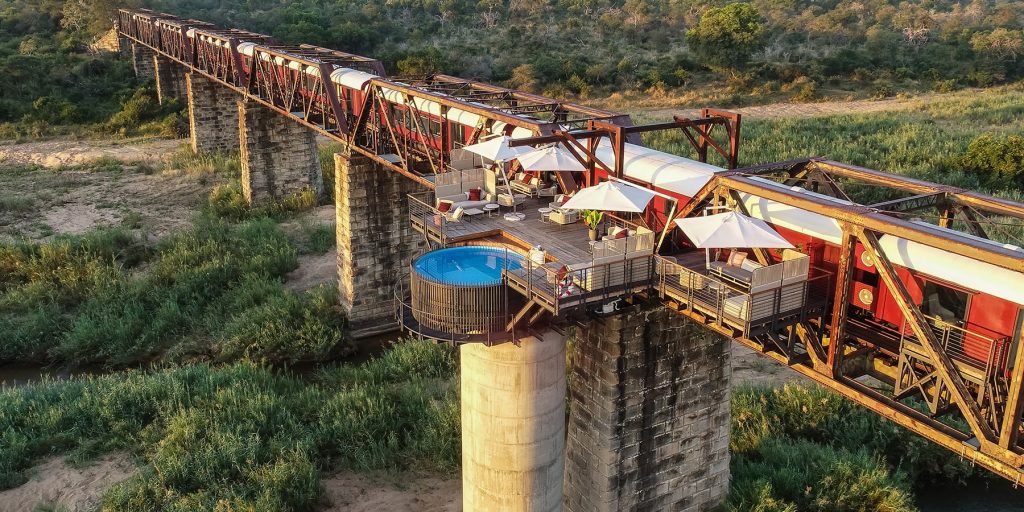 Kruger Shalati Bridge with stationary red and white train and balcony with round pool