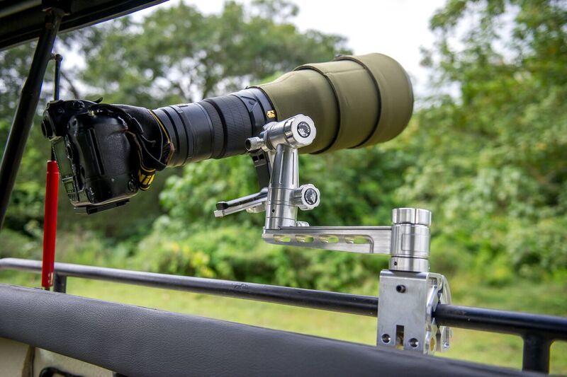 Professional camera with large telescopic lens setup on railing overlooking lush African landscape