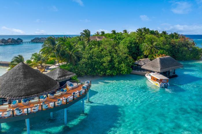 Overwater chalets and lush island with azure blue water
