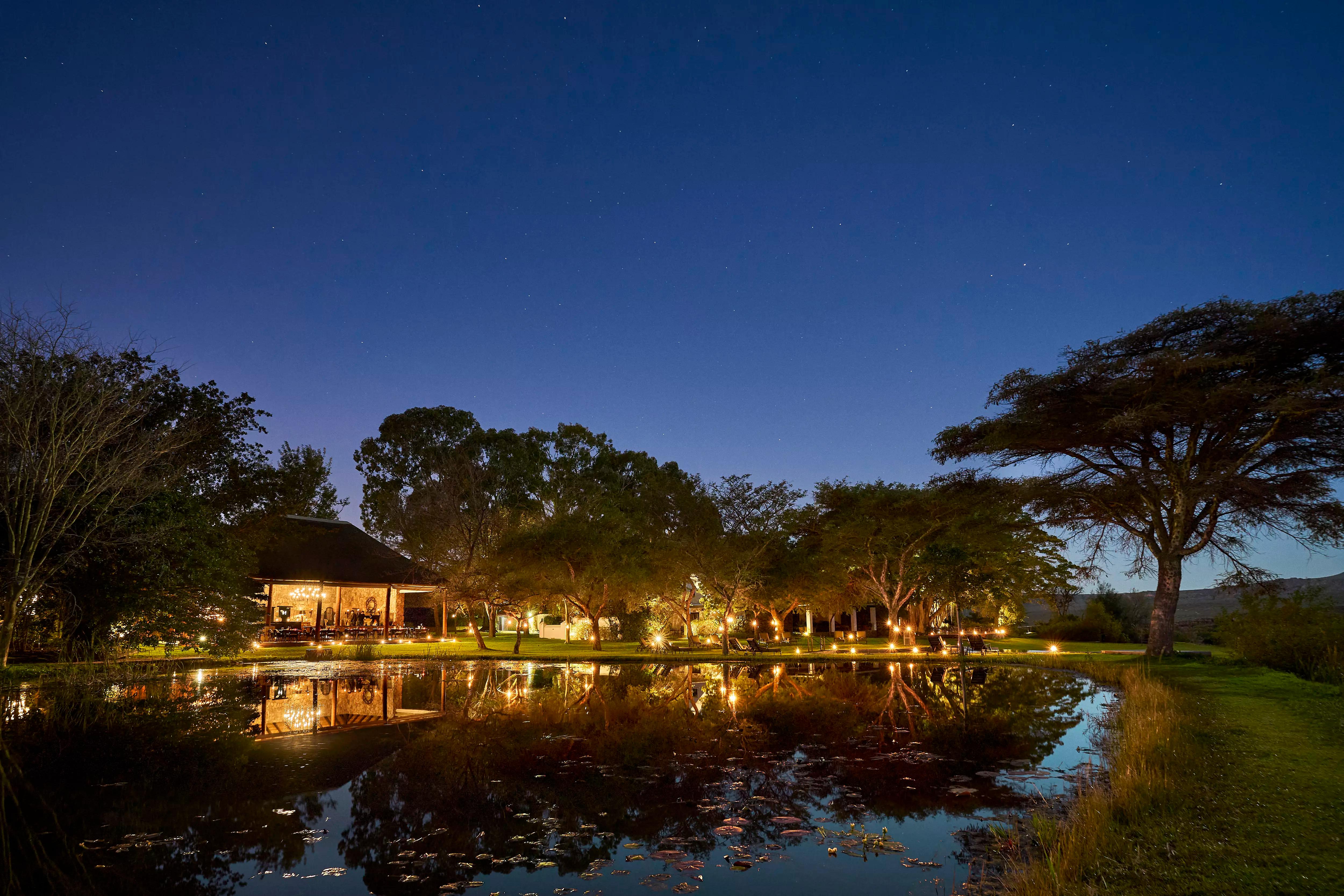 Makana Exterior with lights on at night in front of lake