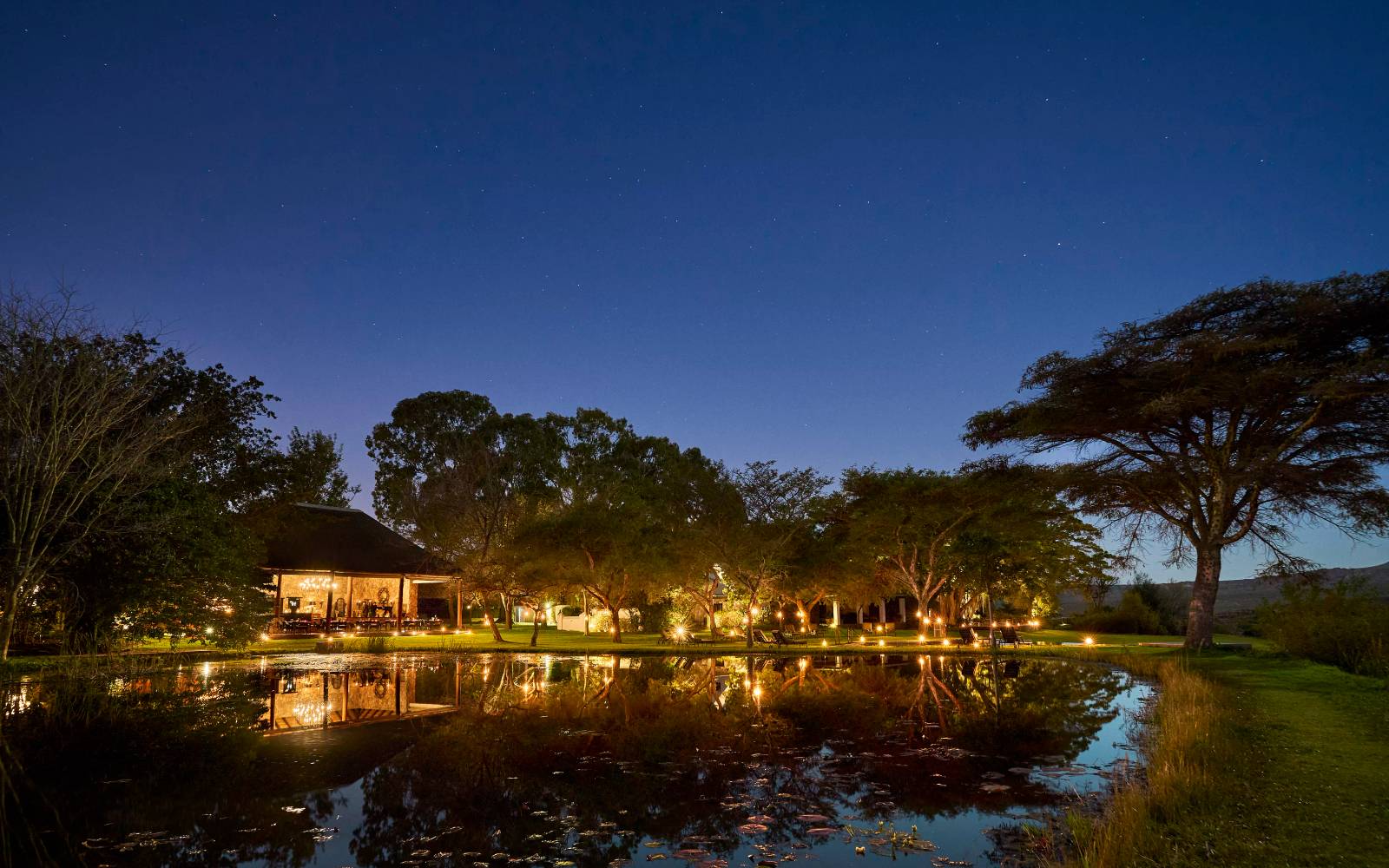 Makana Exterior with lights on at night in front of lake
