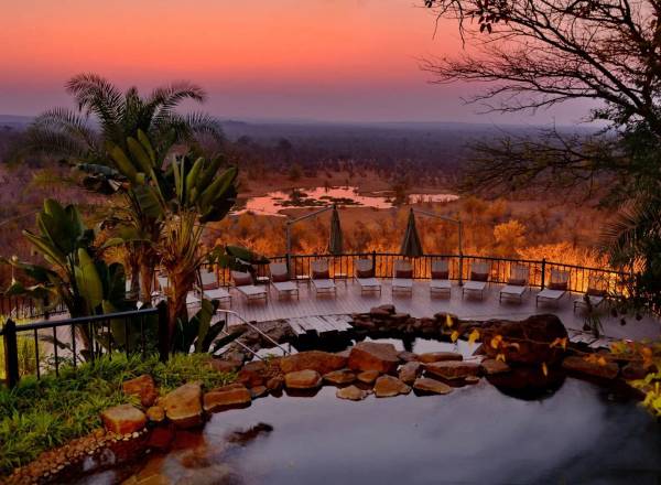 Pool and loungers overlooking African plain after dusk