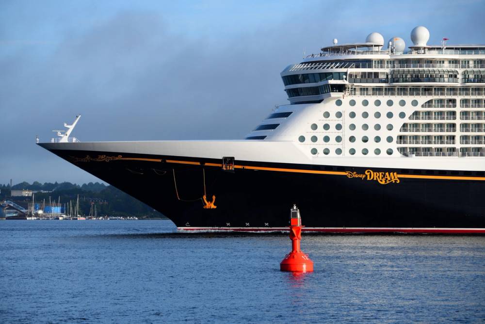 A Disney Dream cruise ship with a black body, yellow "Disney Dream" in writing and white upper deck with many round windows.