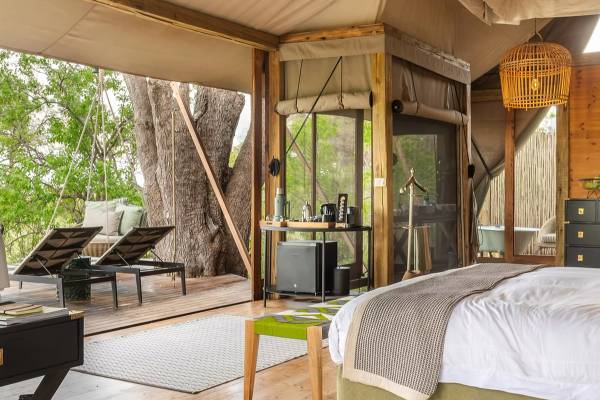 Interior of Tuludi tented suite with double bed overlooking patio with two loungers