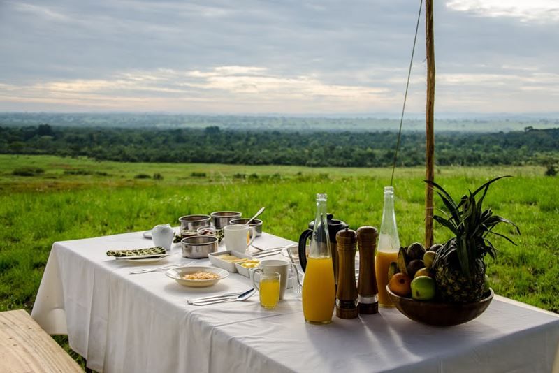 Breakfast table outdoors overlooking lush African landscape