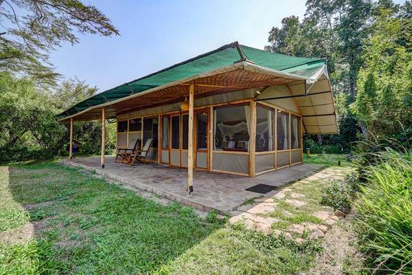 Wooden frame tented luxury suite with patio surrounded by green trees