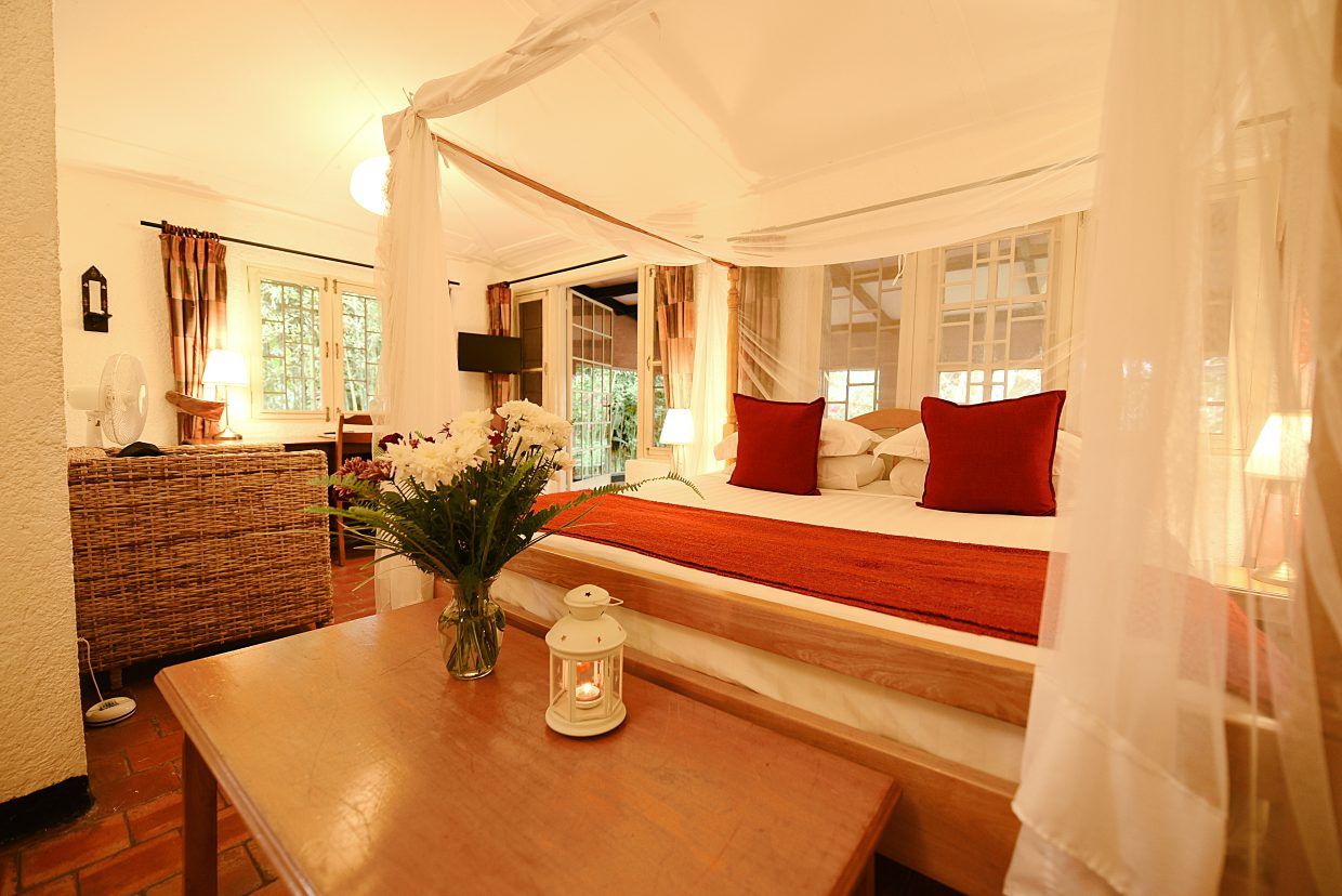 Wooden table at end of double four poster bed with mosquito net