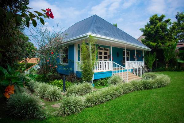 Blue wooden house surrounded by green garden