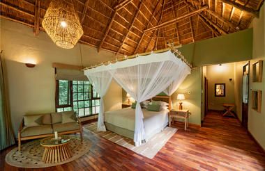 Double volume suite with four poster bed with mosquito net at Primate Lodge Kibale