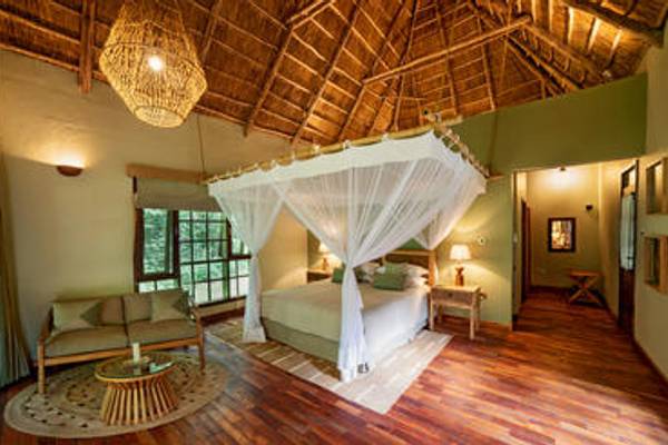 Double volume suite with four poster bed with mosquito net at Primate Lodge Kibale