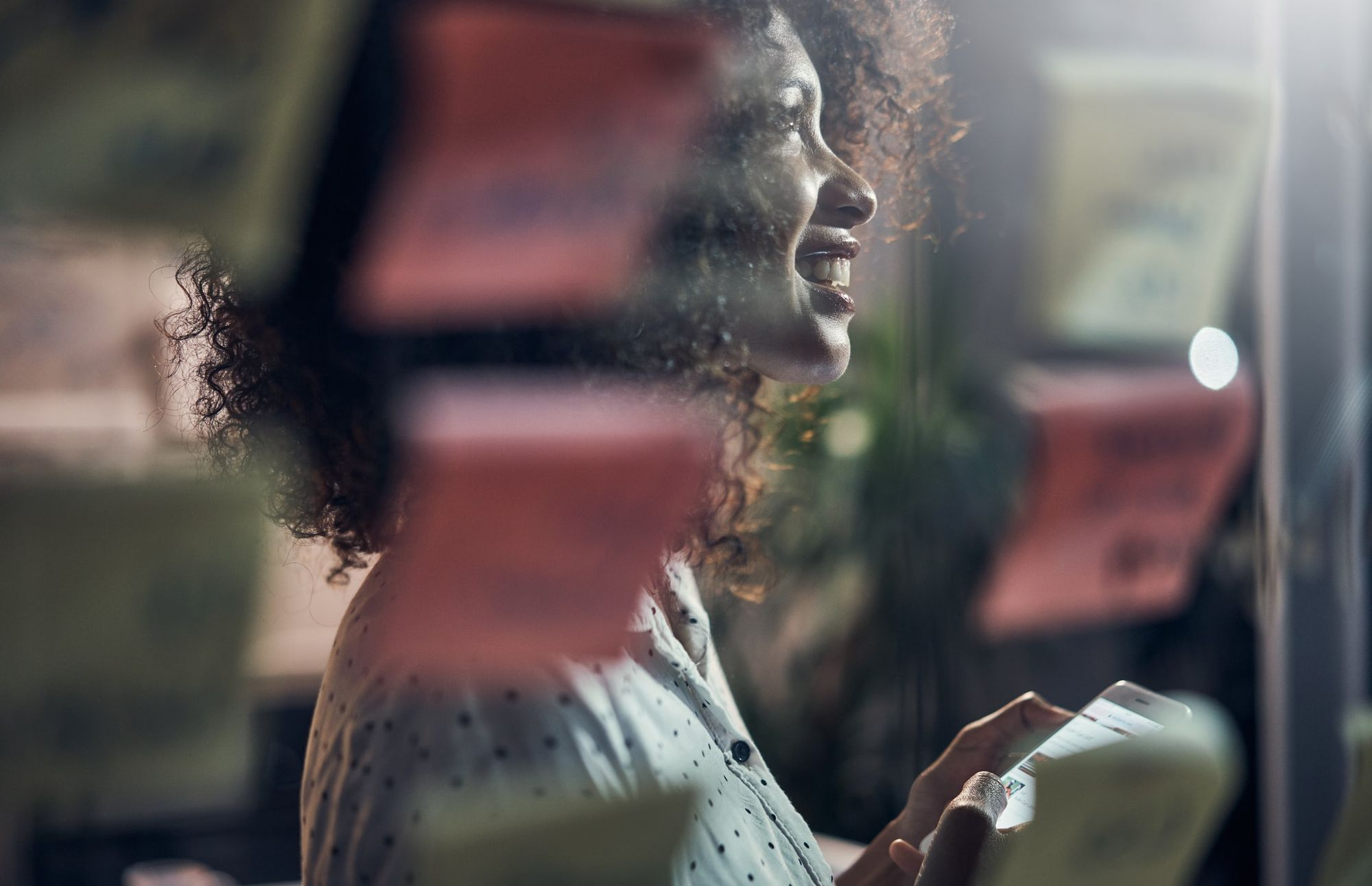 Woman in profile looking through a window, backlit with warm light