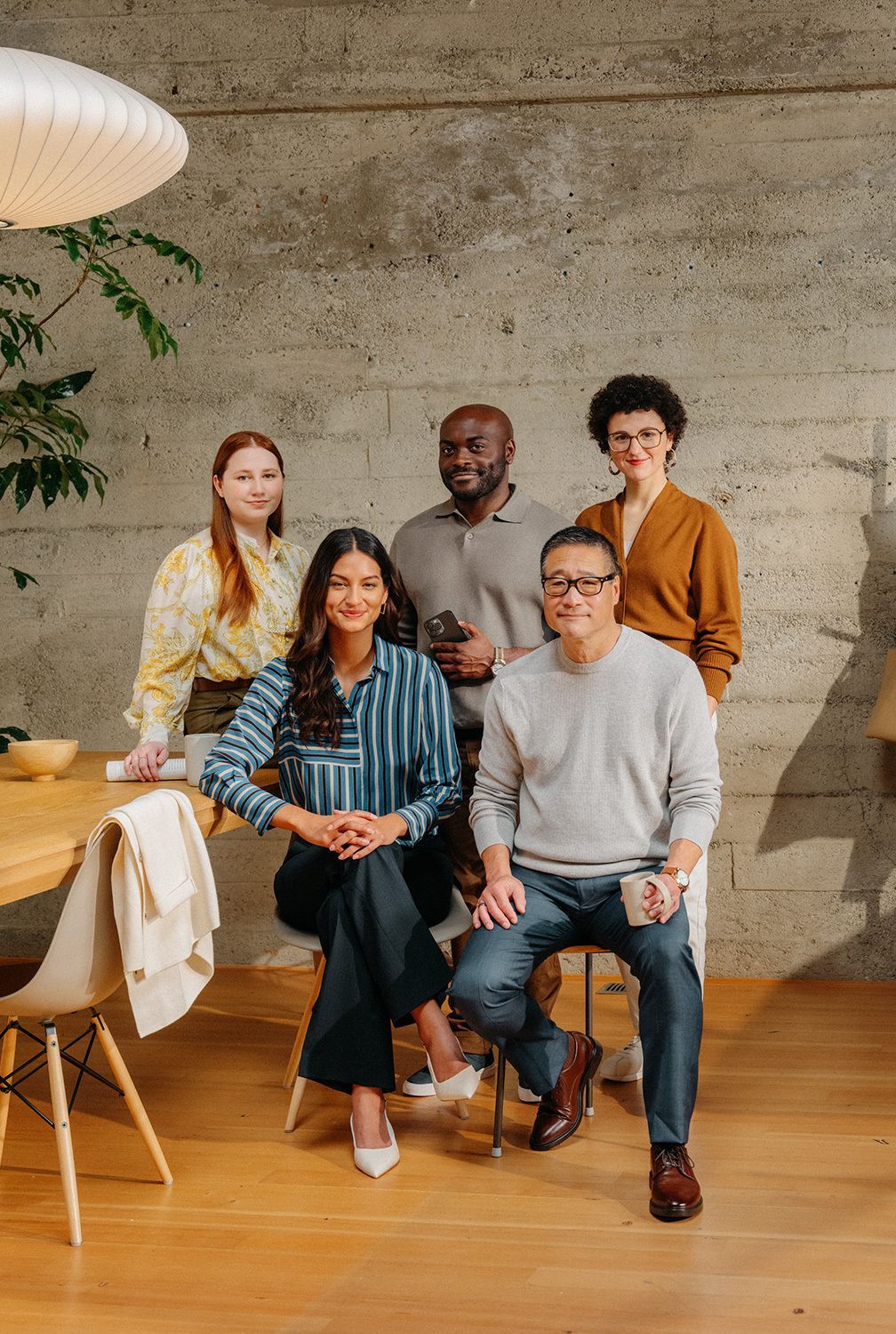 Six colleagues posing together around a table in an office
