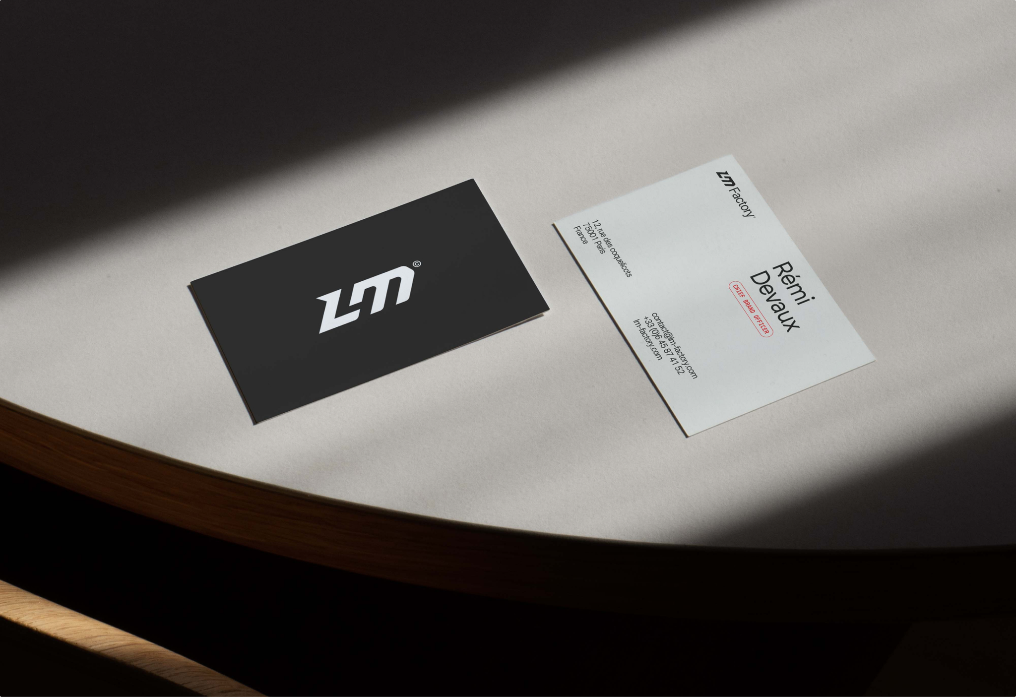 Black and white LM Factory business cards on a table