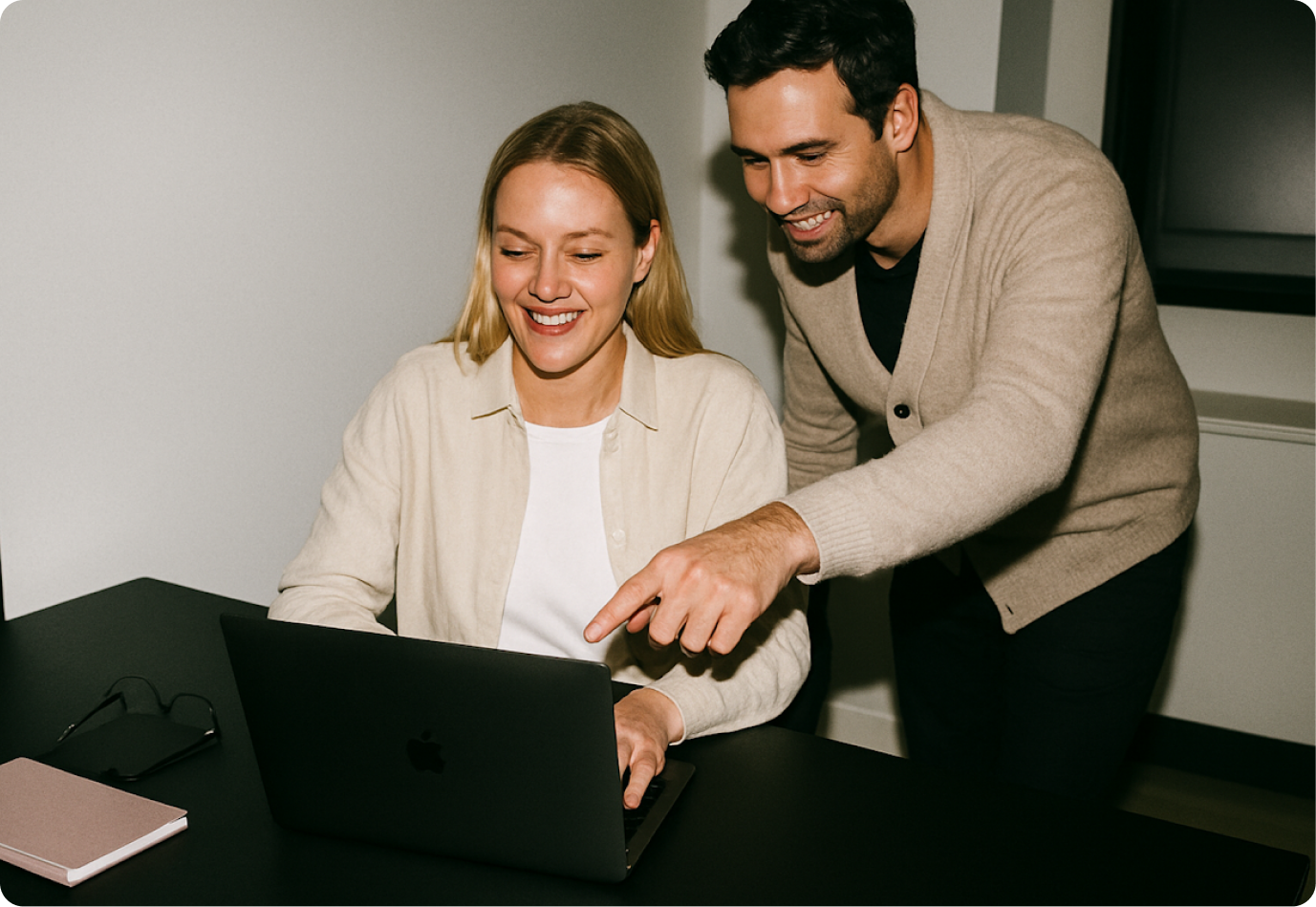 Two colleagues smiling at a laptop
