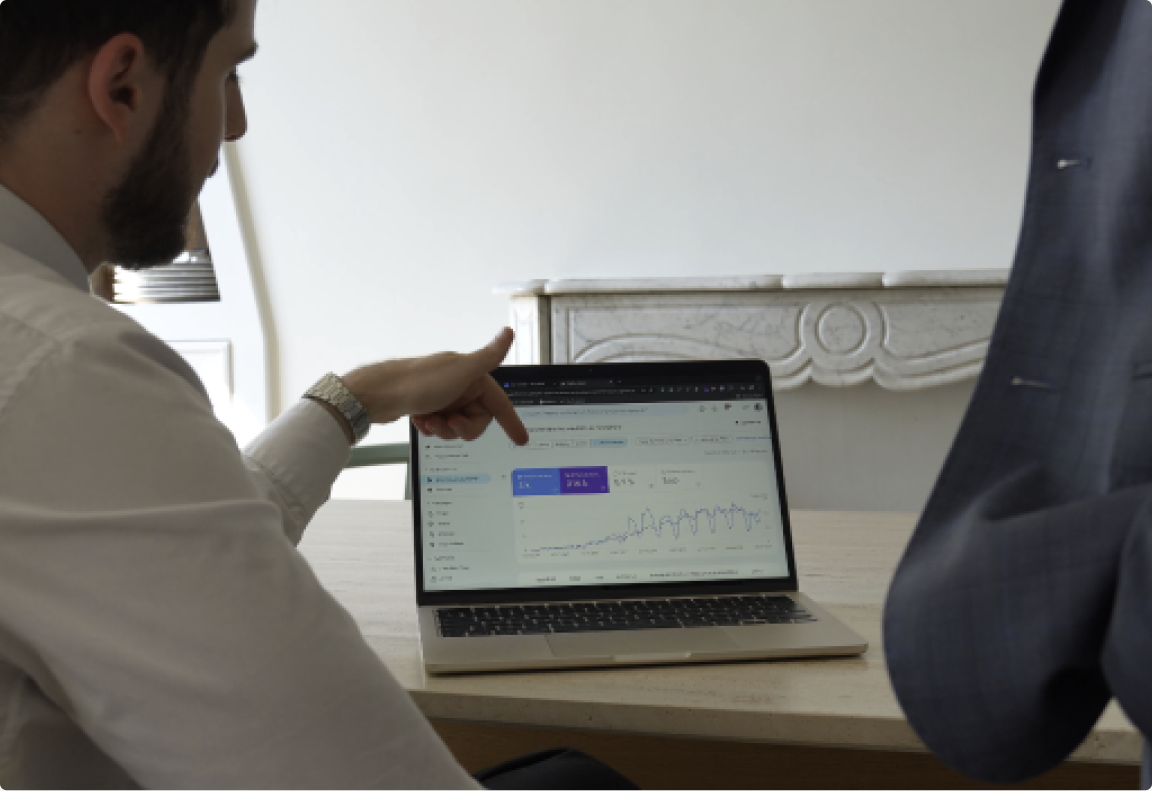 A consultant pointing at a search performance dashboard on a laptop