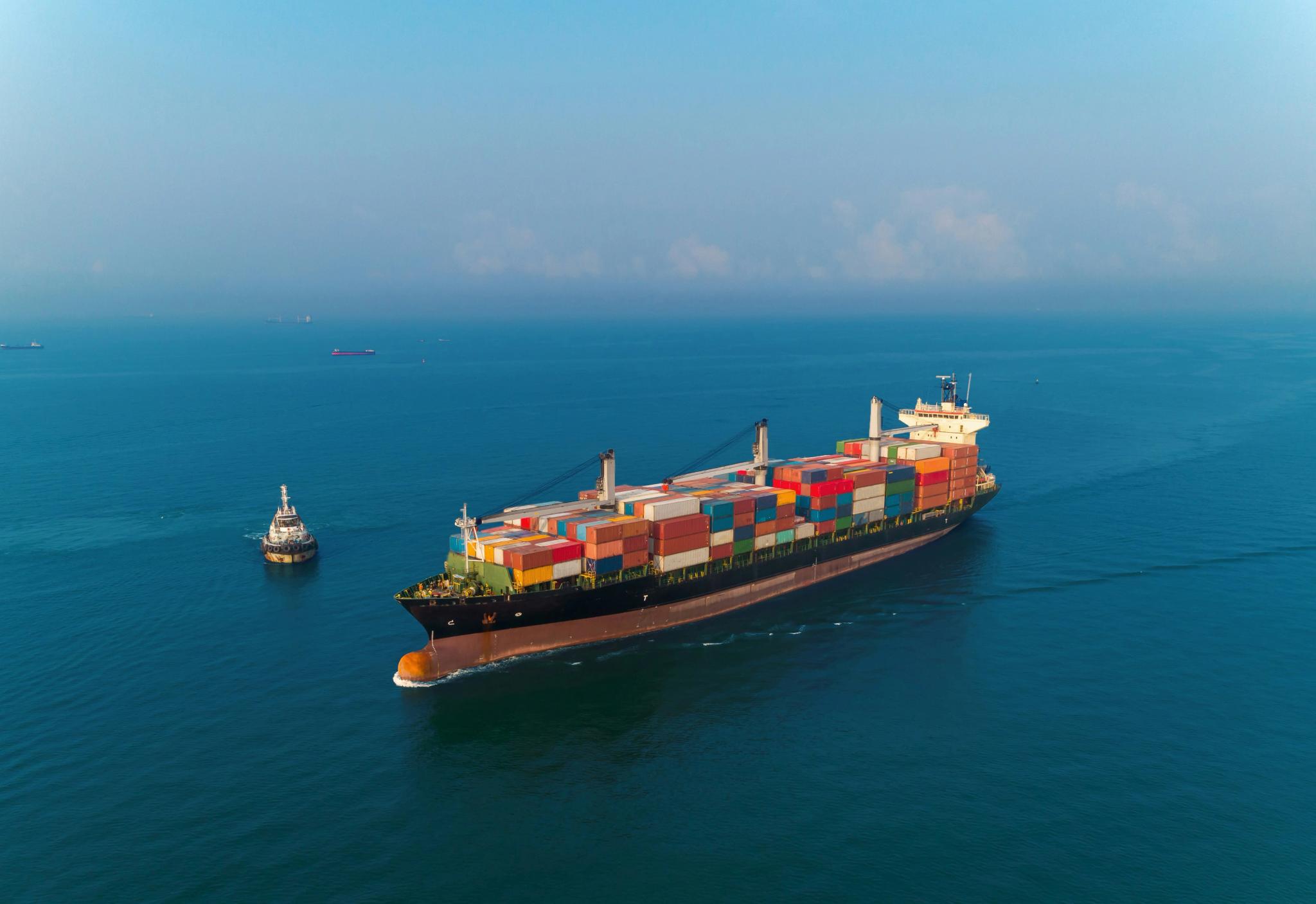 Aerial view of a container ship and a tugboat at sea