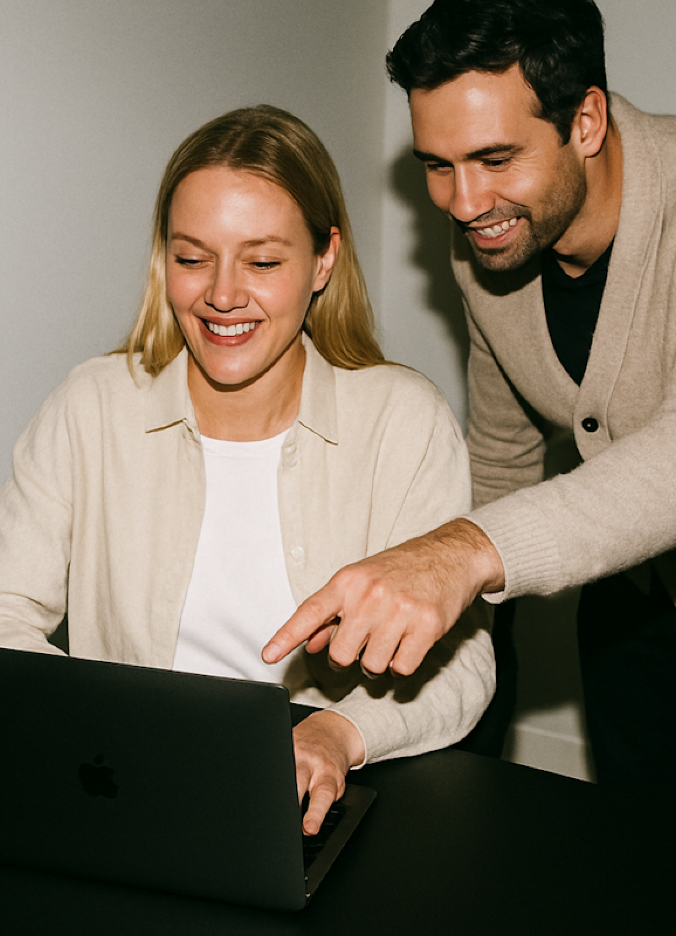 Two colleagues smiling at a laptop