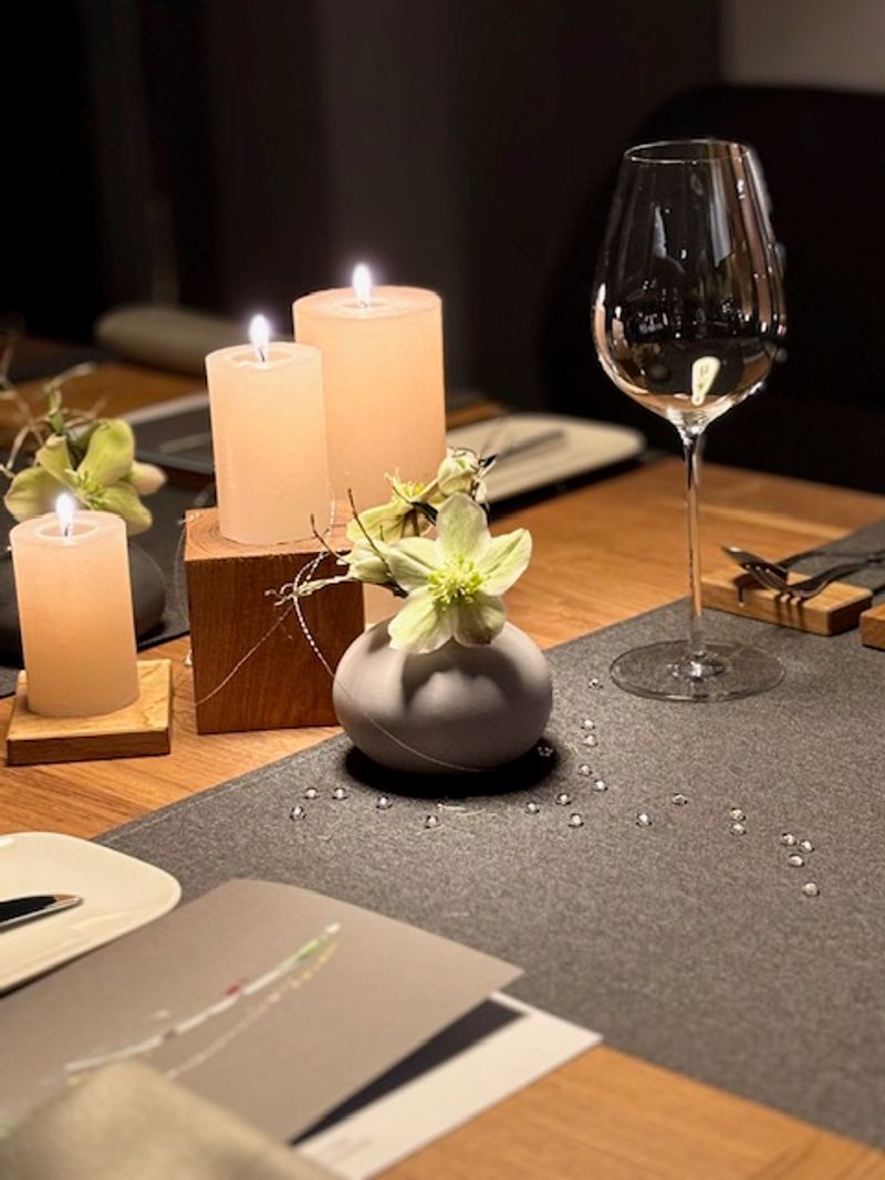 Gedeckter Tisch mit Weinglas, Kerzen und Blumen