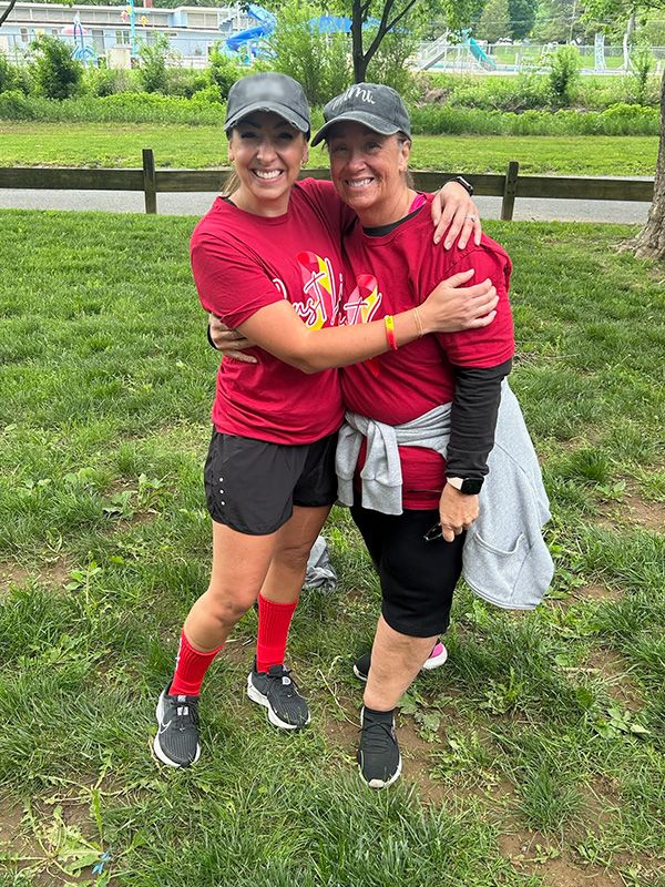 Two ladies take a photo together in their red team shirts
