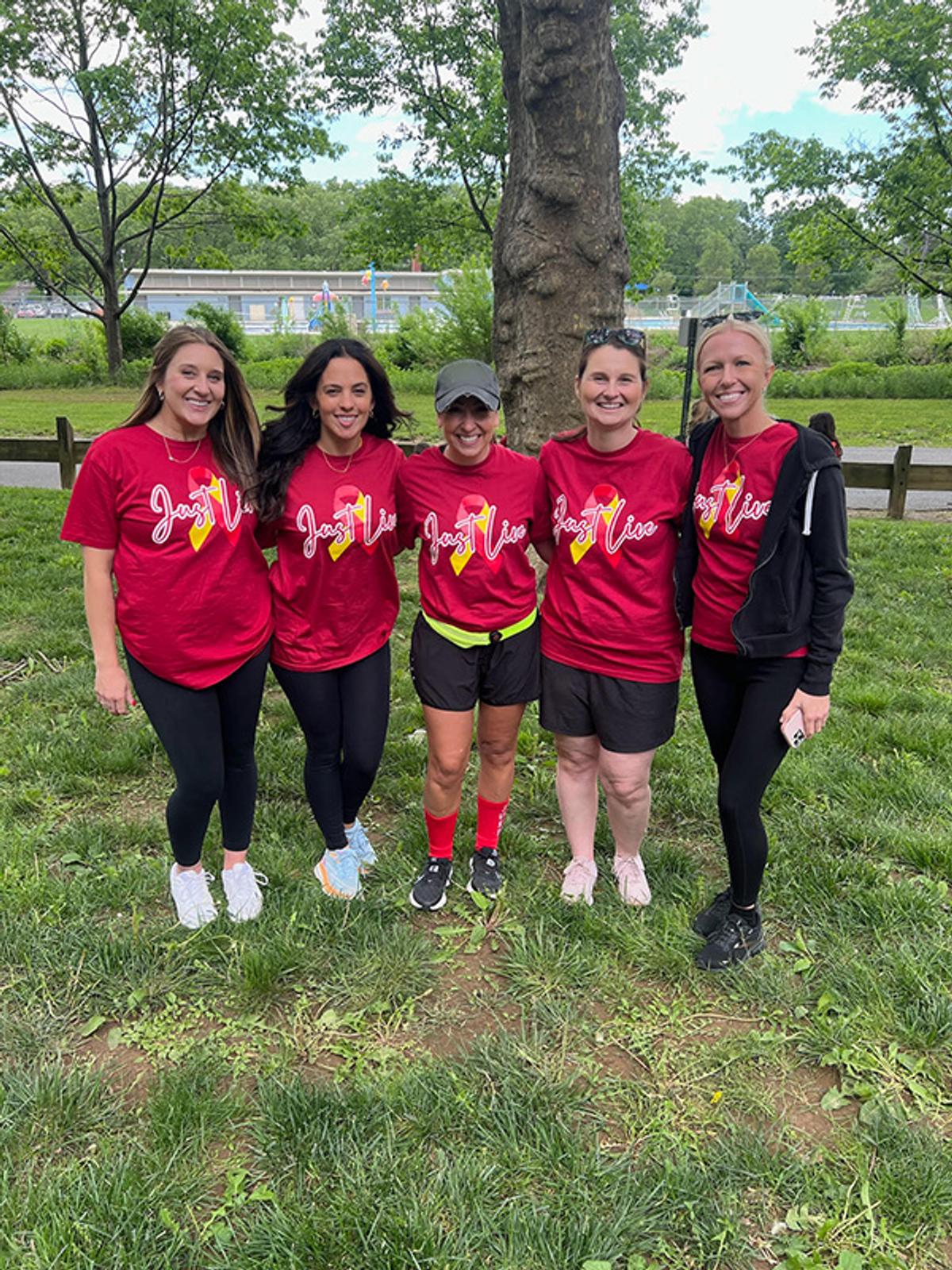 A group of woman pose for a photo in their red team shirts