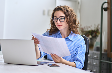 woman holding medical bills in front of her computer
