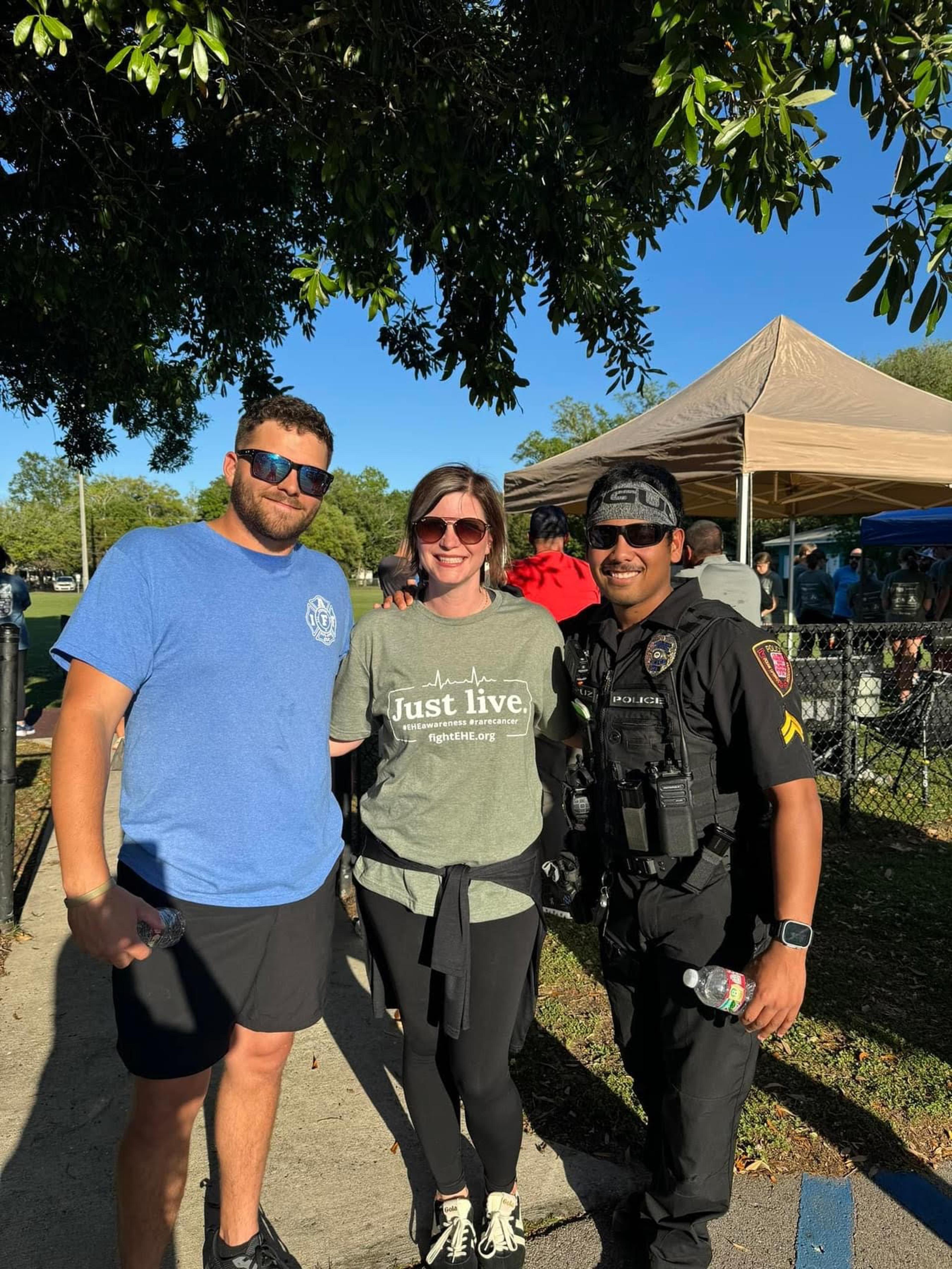 A woman and wife pose for a photo with a police officer