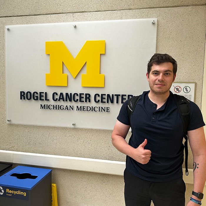 Justin standing in front of Rogel Cancer Center sign