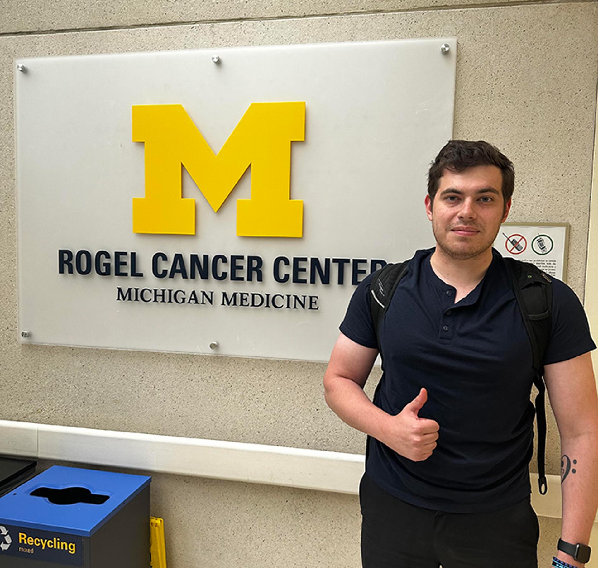 Justin standing in front of Rogel Cancer Center sign