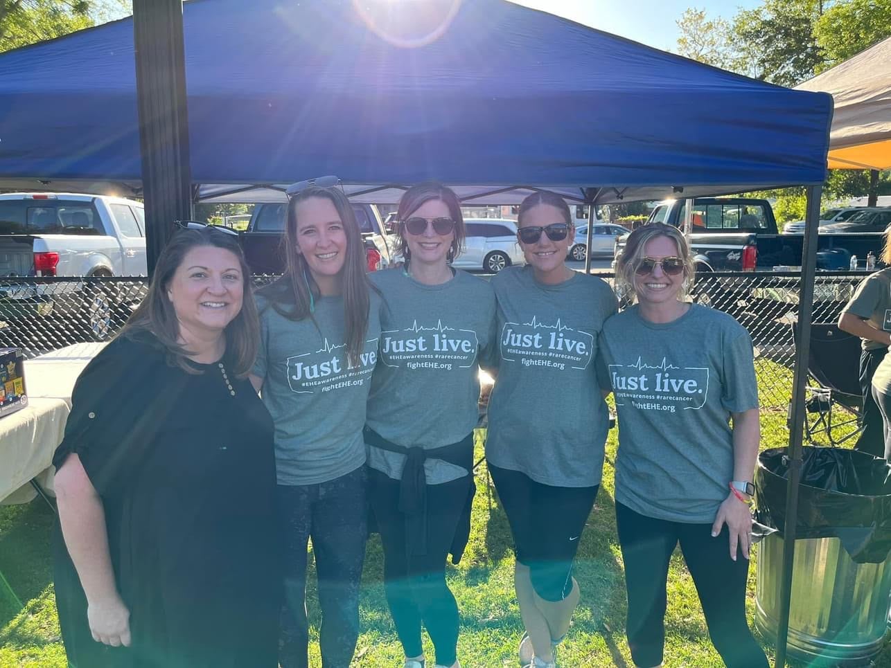 a group of mothers pose for a photo in matching shirts