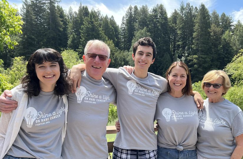 A family comes together for a photo in front of a forest