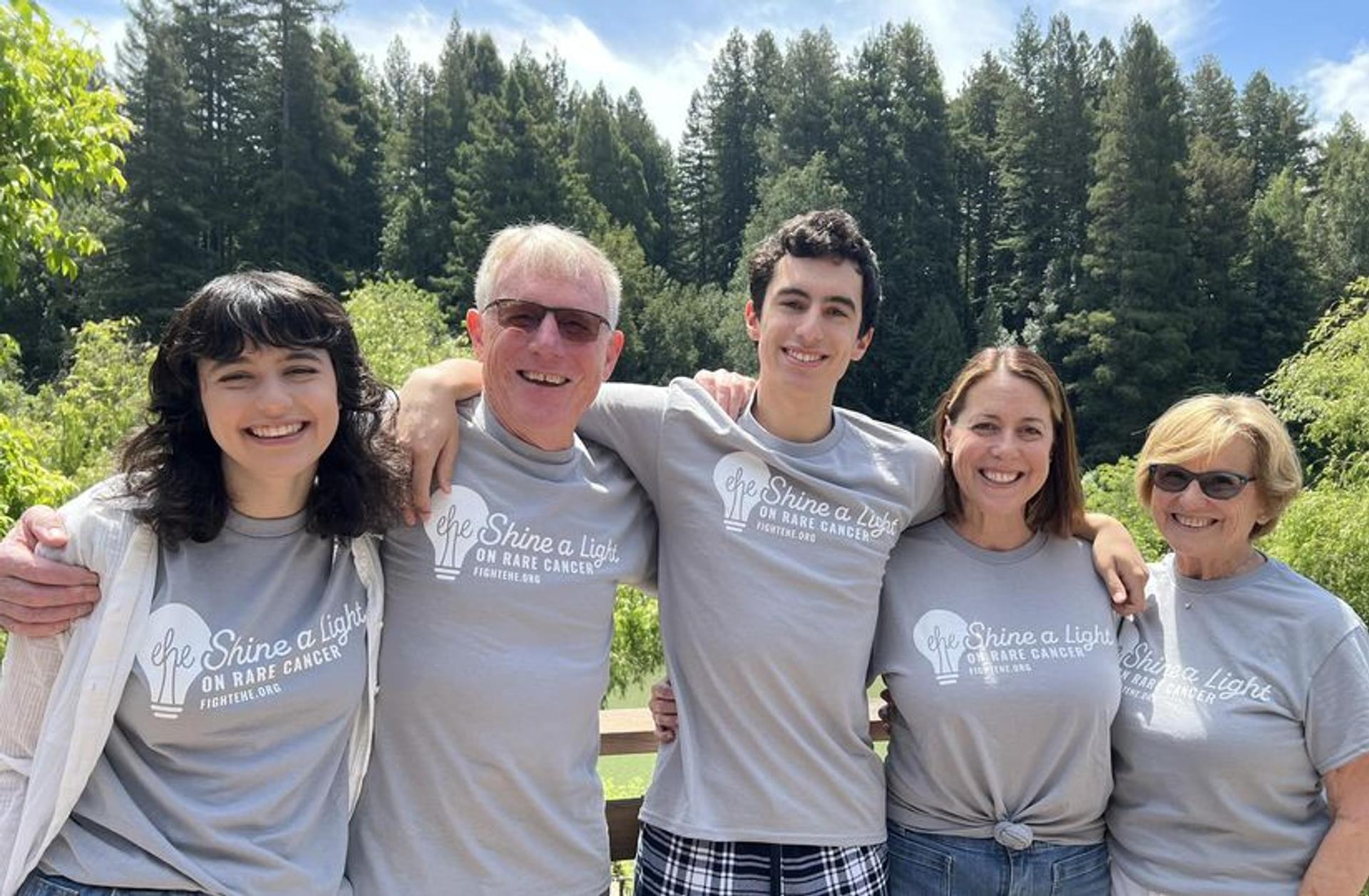 A family comes together for a photo in front of a forest
