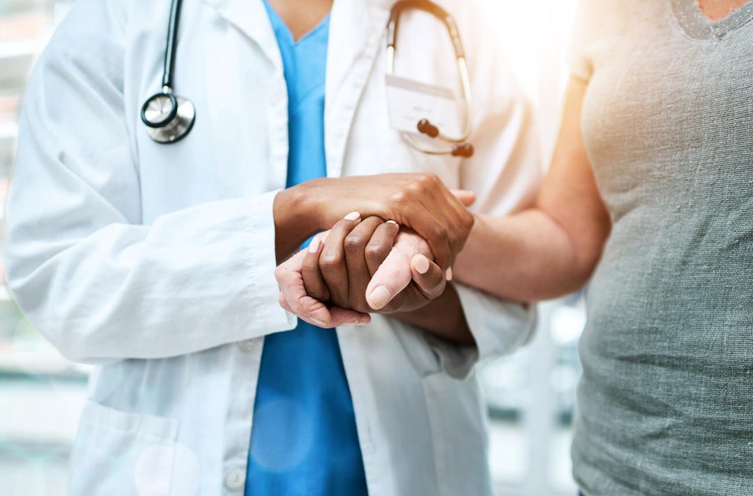 A doctor holding the hand of a patient.