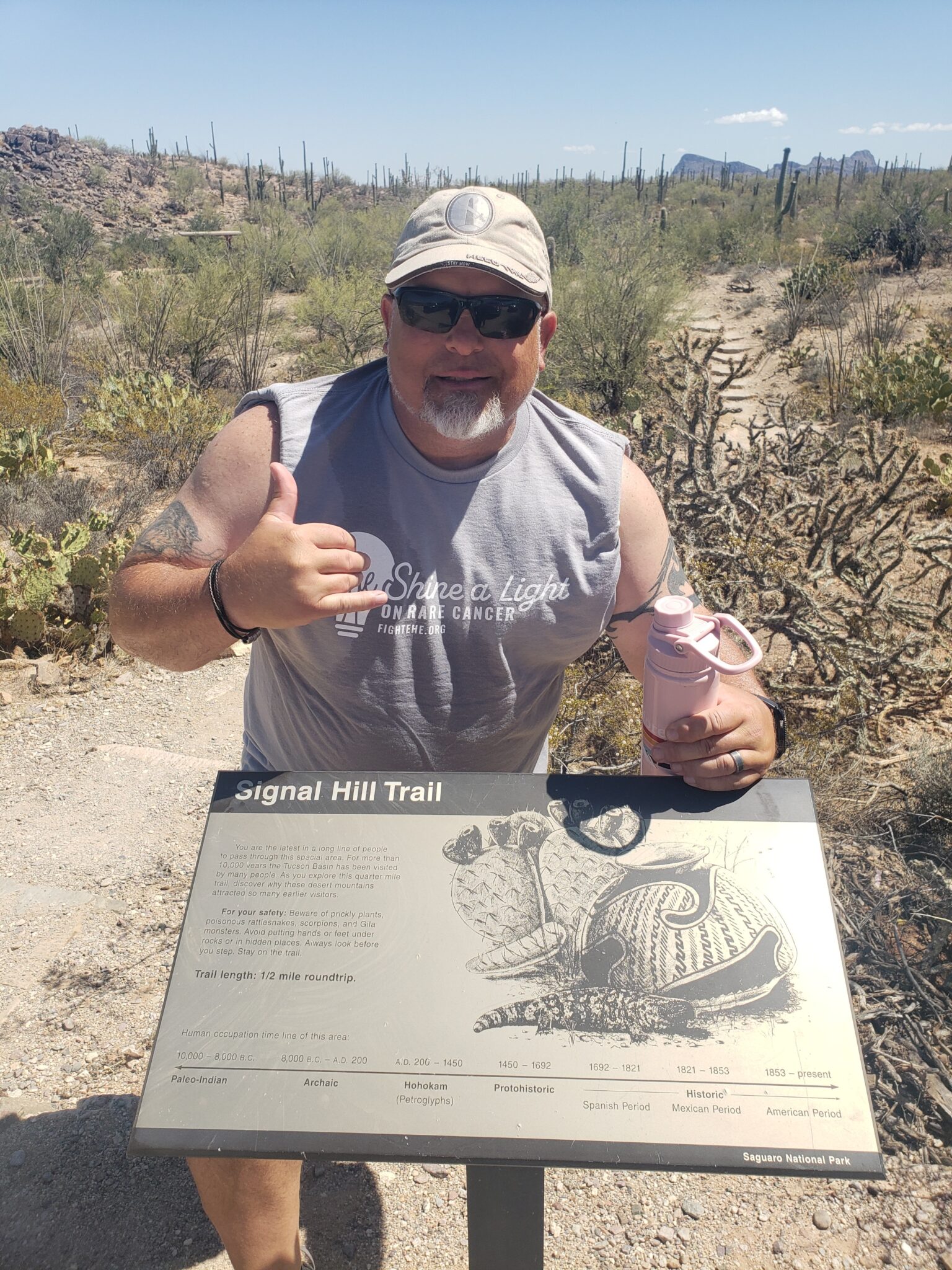 meyers posing with a shaka hand at the trail head sign