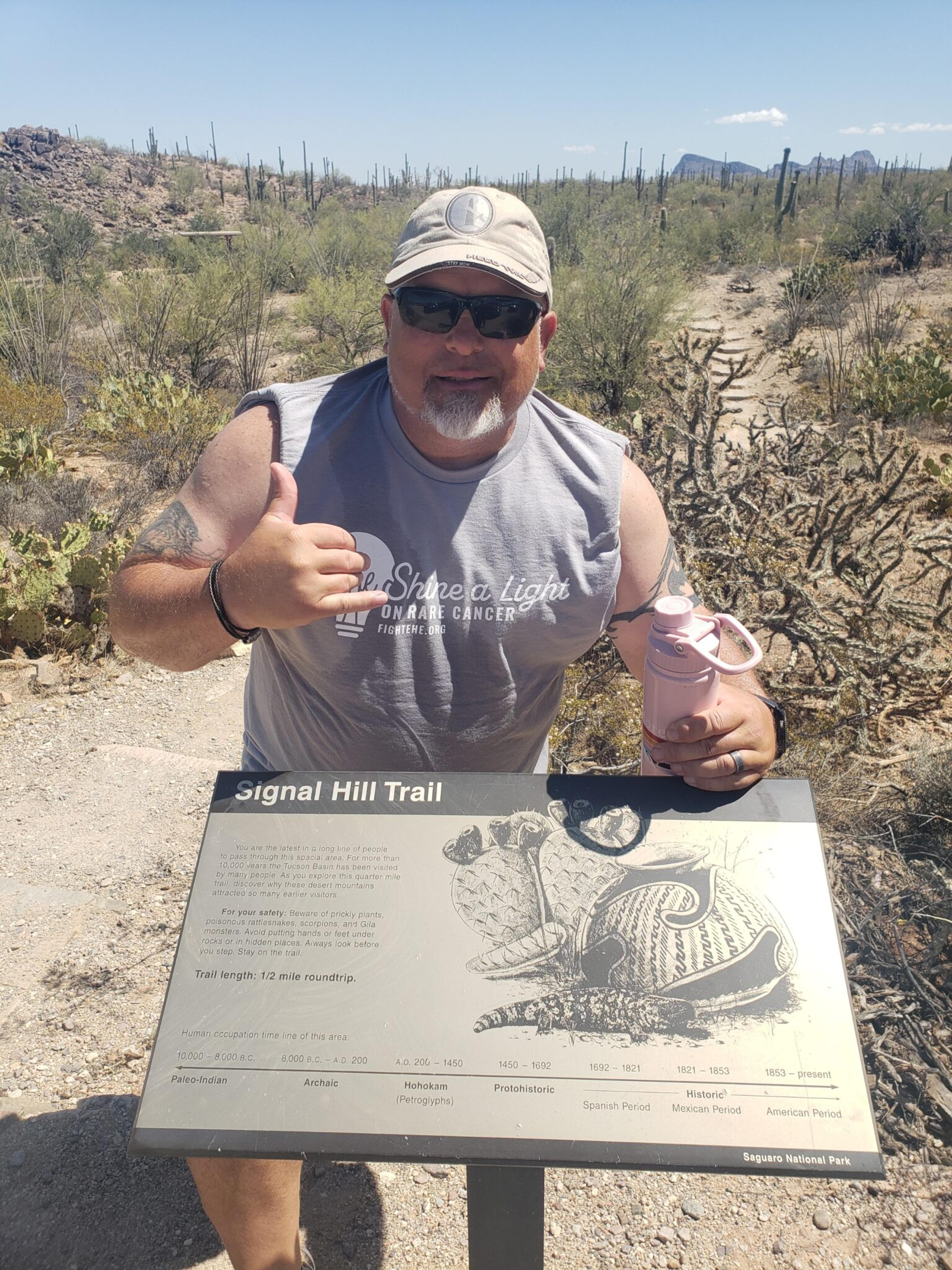 meyers posing with a shaka hand at the trail head sign
