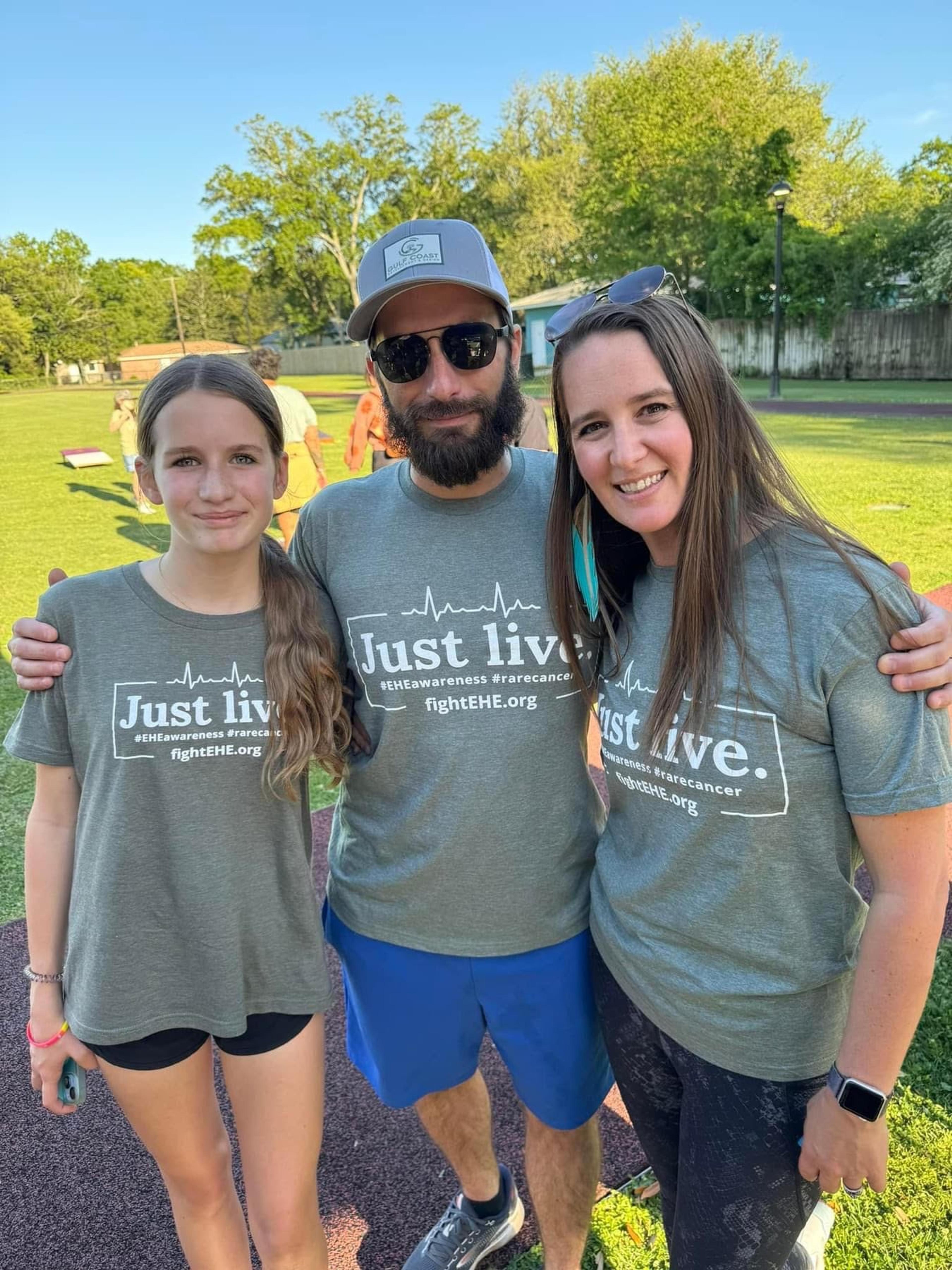 A famile smiles for a photo in matching tshirts