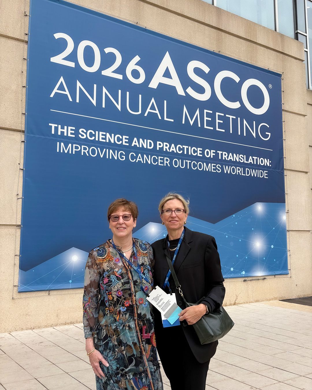 Barbara Van Hare and Denise Robinson standing in front of an ASCO banner